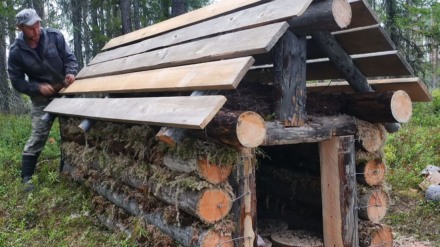 为了抵御森林中野兽的侵袭，男人利用粗壮的原木，为自己搭建出防