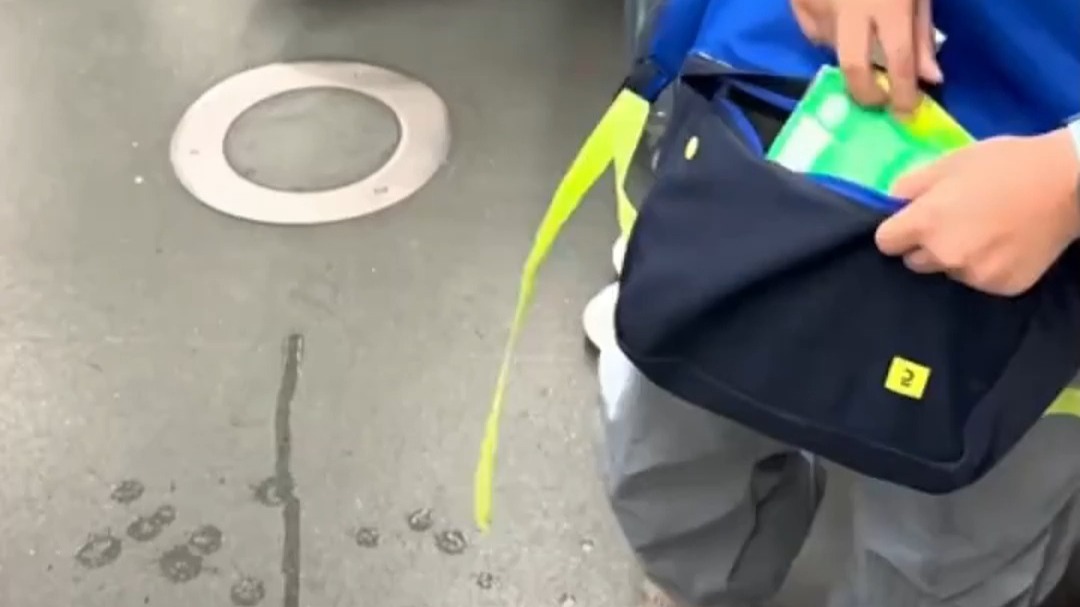 小男孩不慎将饮料洒在地铁上，掏出纸巾认真擦干净。