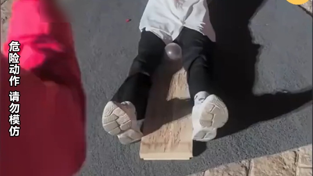 小伙把气球夹两腿之间  随后飞刀将气球击破