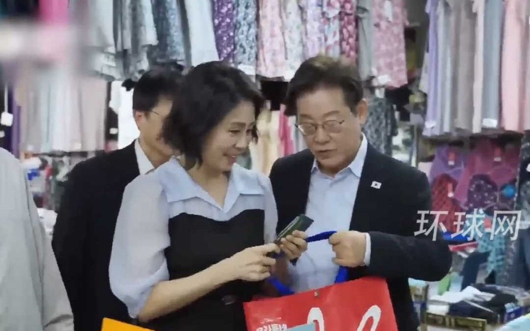 李在明走访首尔市场，与夫人一起试吃糕点，现场掏钱购物后给夫人